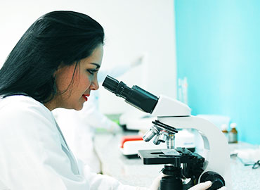 woman looking through a microscope