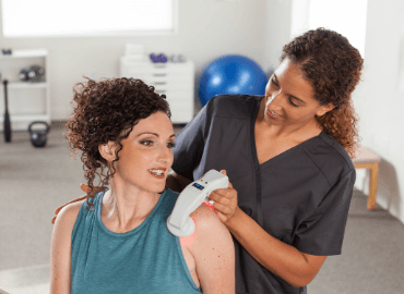 woman dr treating a female patients shoulder with the lumacare duo
